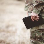 Shallow focus shot of a young soldier holding a bible in a field