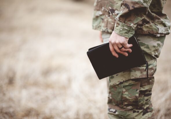 Shallow focus shot of a young soldier holding a bible in a field