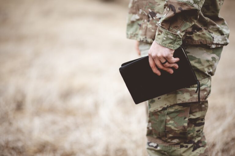 Shallow focus shot of a young soldier holding a bible in a field